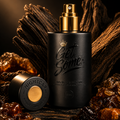 A matte black cylindrical perfume bottle with a gold spray top and the words 'Get Some.' on the front, styled with a matching cap beside it on a dark surface surrounded by amber crystals and wood.