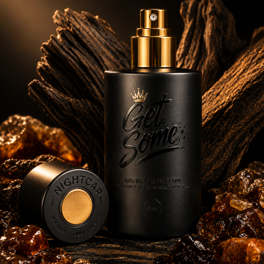 A matte black cylindrical perfume bottle with a gold spray top and the words 'Get Some.' on the front, styled with a matching cap beside it on a dark surface surrounded by amber crystals and wood.